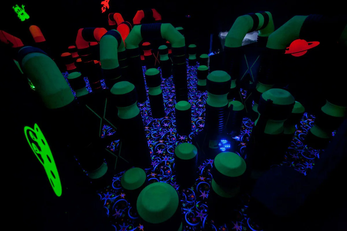 Black-light laser tag arena with glowing obstacles at Southern Lanes